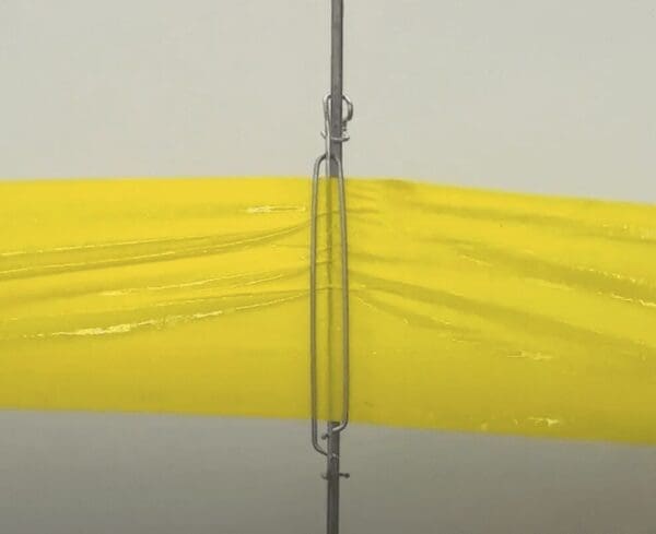 Yellow plastic barrier secured by metal pole and fastener on light grey background.